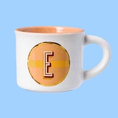 Caneca de cerâmica branca com círculo cor-de-pêssego e letra E impressa na frente