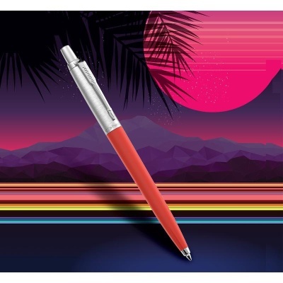 Caneta esferográfica vermelha e metalizada sobre fundo gráfico colorido