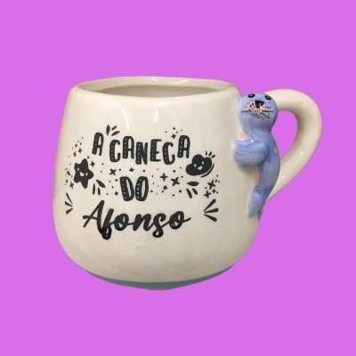 Caneca branca com texto e figura decorativa de foca azul na alça