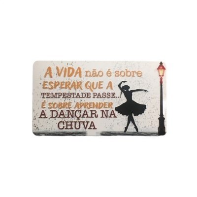 Placa decorativa com texto inspirador, bailarina preta e candeeiro vermelho.
