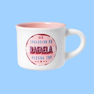 Caneca branca com interior rosa e texto personalizado em frente, sobre fundo azul claro