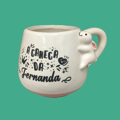 Caneca branca de cerâmica com alça em forma de coelho e texto personalizado.