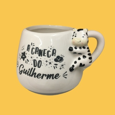 Caneca branca cerâmica com alça de vaca e texto 'A CANECA DO Guilherme'