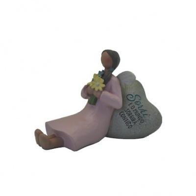 Estatueta de mulher sentada em vestido rosa com pedra em forma de coração com texto em português.