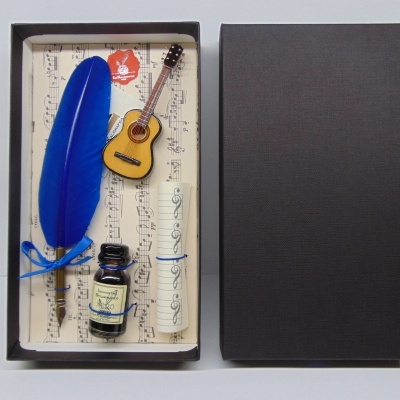 Kit de escrita com pena azul, tinteiro, miniatura de guitarra e pergaminho numa caixa preta