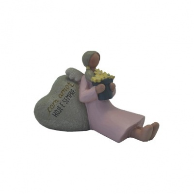 Figura decorativa de anjo sentado com vaso de flores e coração cinzento com texto.