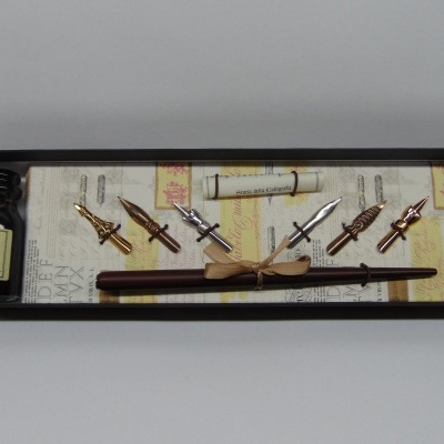 Conjunto de caligrafia com tinteiro, penas metálicas, pena de madeira e suporte de papel numa caixa preta