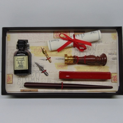 Conjunto de escrita antiga com tinteiro, caneta, selo, bloco e pergaminho numa caixa preta