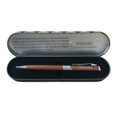 Caneta castanha e prata numa caixa metálica prateada com texto em português sobre Daniel