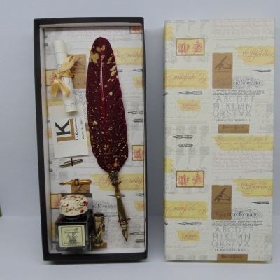 Conjunto de escrita com pena vermelha, tinteiro e suporte dentro de caixa decorada