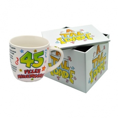 Caneca branca com decoração colorida de aniversário e caixa correspondente com logo ATUALIDADE.