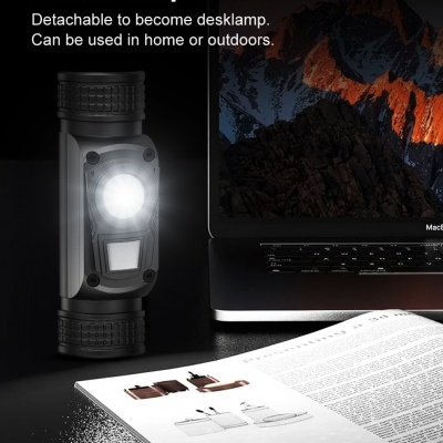 Lanterna preta com luz branca ligada ao lado de computador portátil e livro aberto