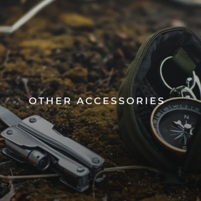 Acessórios ao ar livre sobre terra com raízes, incluindo bolsa verde, bússola, ferramenta multiuso e objeto vermelho com corda.