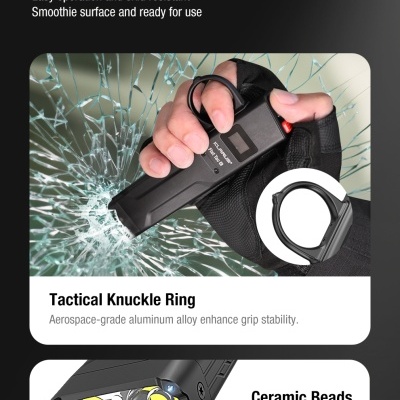 Dispositivo tático preto com anel de punho e contas cerâmicas, usado para quebrar vidro com vidro partido ao fundo