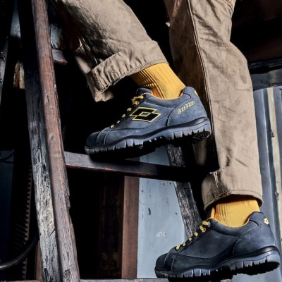 Calçado desportivo preto com atacadores amarelos usado em ambiente industrial