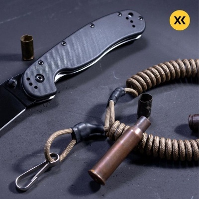 Faca de bolso cinzenta, cordão trançado bege e cartuchos de munição sobre superfície escura