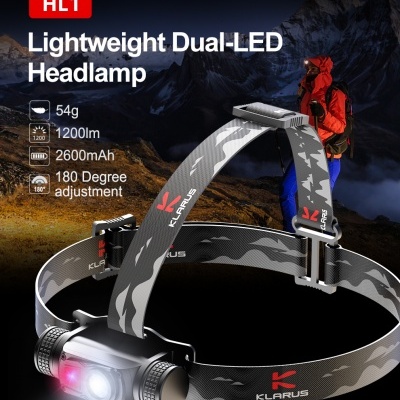 Lanterna frontal HL1 KLARUS camuflada cinza e preta com luz LED acesa e cenário de montanha ao fundo