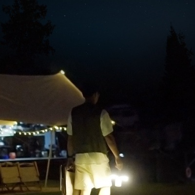 Pessoa a caminhar ao anoitecer com lanterna portátil iluminando o chão