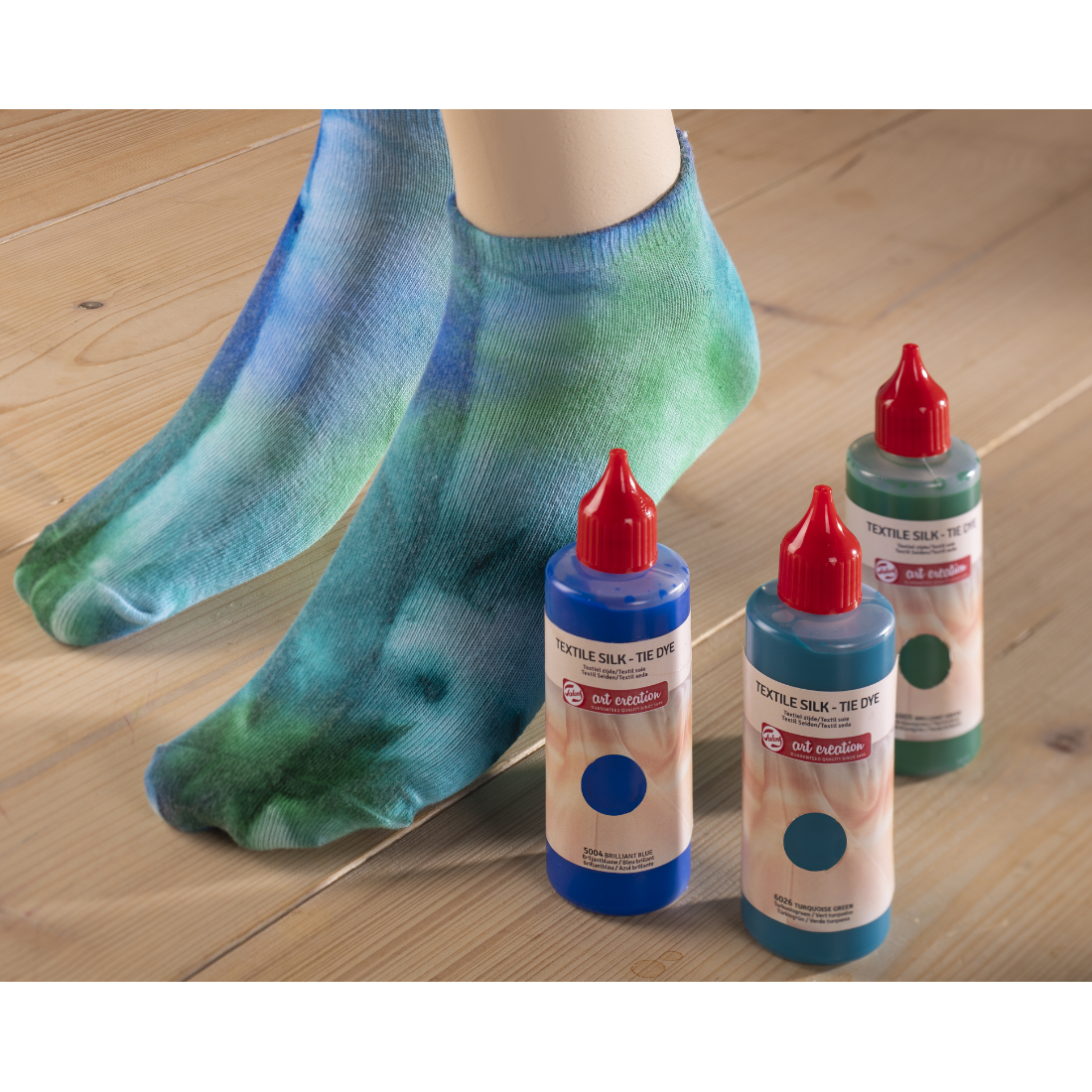 Meias tie-dye azuis e verdes com corantes têxteis em frascos ao lado