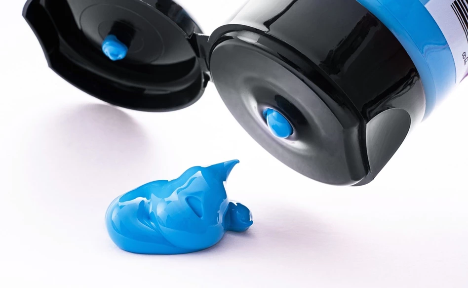 Tubo preto com tinta azul vibrante sobre fundo branco