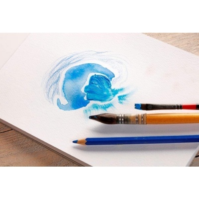 Folha de papel com pintura azul, pincéis e lápis azul sobre mesa de madeira