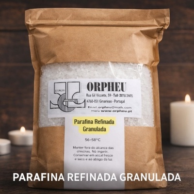 Saco de papel com parafina granulada branca e etiquetas em português, com velas acesas ao fundo