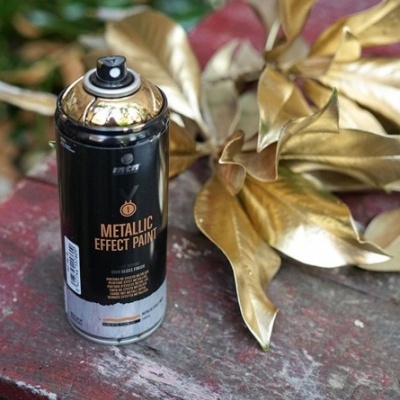 Spray de tinta metálica preta com texto ao lado de folhas douradas
