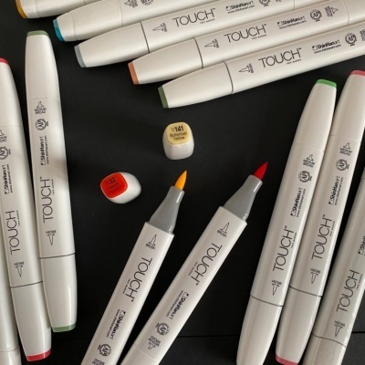 Marcadores Touch Twin Marker coloridos com pontas de pincel sobre superfície preta