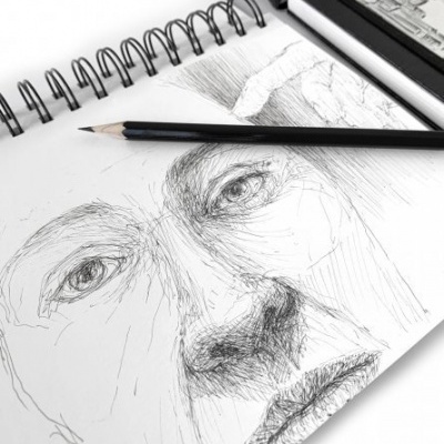 Caderno de desenho espiral aberto com esboço de rosto e lápis preto