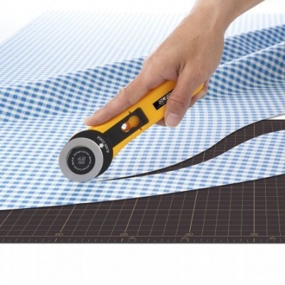 Roda de corte amarelo e preto a cortar tecido xadrez azul e branco