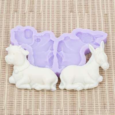 Molde de silicone roxo com figuras brancas de vaca e burro sobre tecido de palha