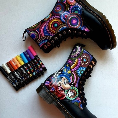 Botas pretas com design colorido e Mickey Mouse, com canetas coloridas ao lado