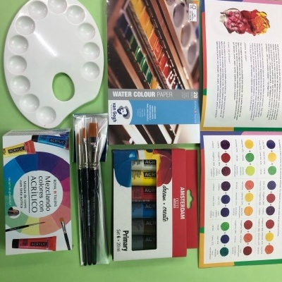 Materiais de pintura artísticos incluindo paleta, pincéis, papel de aguarela, tintas acrílicas e guia de mistura de cores