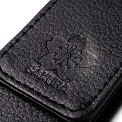 Capa preta texturizada com gravação em relevo de flor e palavra SAKURA