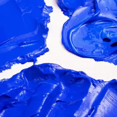 Tinta acrílica azul vibrante com textura espessa sobre fundo branco.