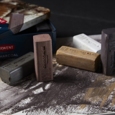 Blocos de carvão para desenho em várias cores sobre superfície manchada com pó