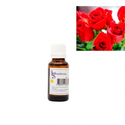 Frasco pequeno de essência ao lado de rosas vermelhas frescas