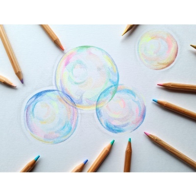 Lápis de cor em círculo à volta de desenhos de bolhas coloridas em papel branco