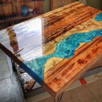 Mesa de madeira e resina azul com suporte metálico em ambiente interior