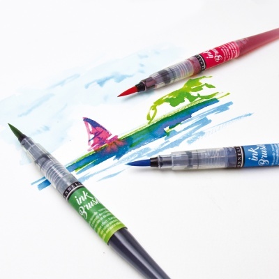 Três pincéis de tinta coloridos sobre papel com desenho