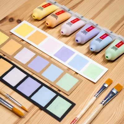 Tinta acrílica colorida, pincéis e amostras de cores em mesa de madeira