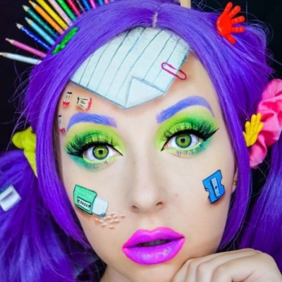 Rosto com maquilhagem vibrante, cabelo roxo e desenhos escolares no rosto