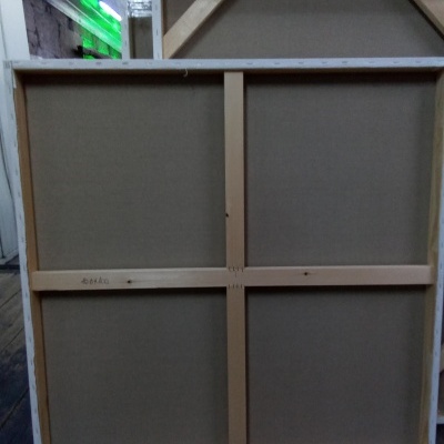 Parte traseira de tela para pintura com estrutura de madeira e tecido bege numa sala semelhante a armazém