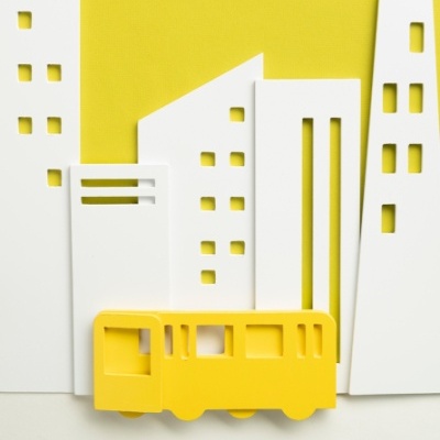 Decoração de parede com edifícios brancos recortados e autocarro amarelo