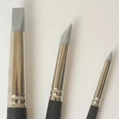 Três pincéis para escultura com cabos pretos e pontas cinzentas