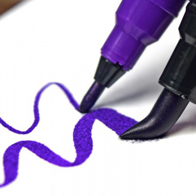 Duas canetas de feltro roxa e preta desenhando linhas onduladas em papel branco
