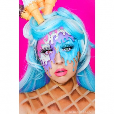 Pessoa com maquilhagem artística de gelado a derreter, peruca azul e cones de gelado no cabelo