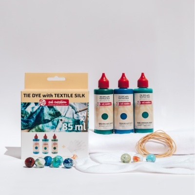 Conjunto tie dye com tinta para seda têxtil, 3 frascos de 85 ml, elásticos e bolas coloridas sobre tecido branco