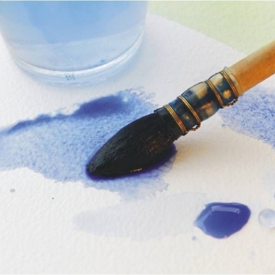 Pincel molhado em tinta azul sobre papel e copo de água