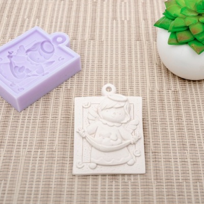 Molde de silicone roxo e pingente branco com padrão decorativo sobre superfície bege com planta suculenta